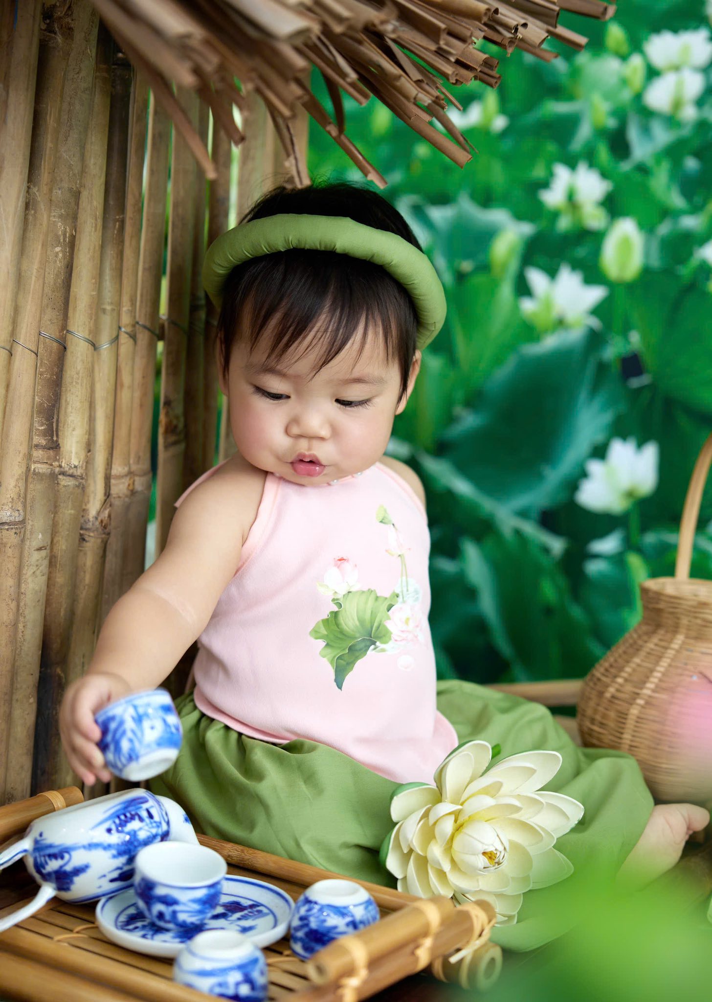 Bé gái ngồi chơi bên bàn trà và hoa sen