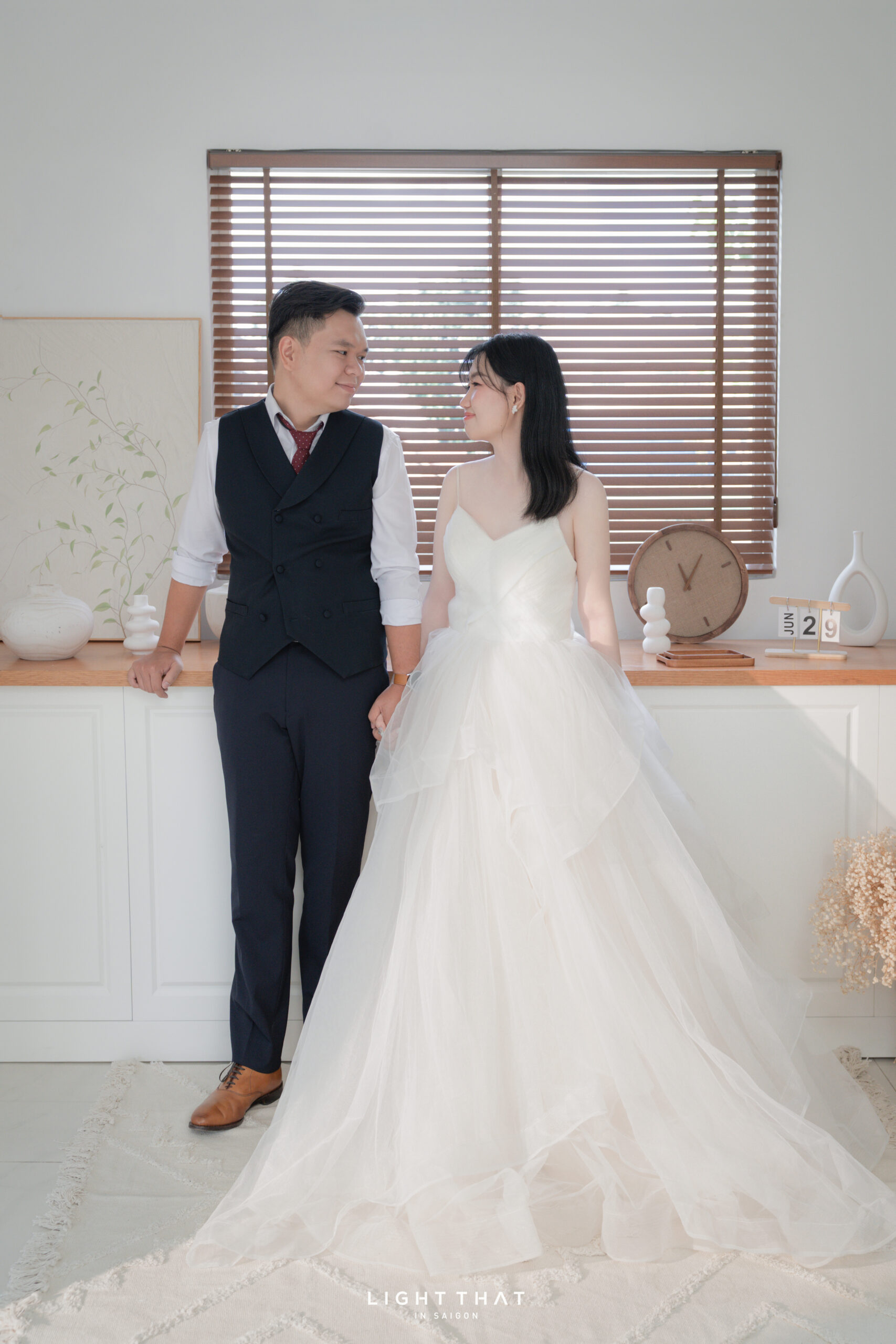 Cô dâu chú rể ngồi giữa vườn hoa, ánh sáng tự nhiên, biểu cảm dịu dàng