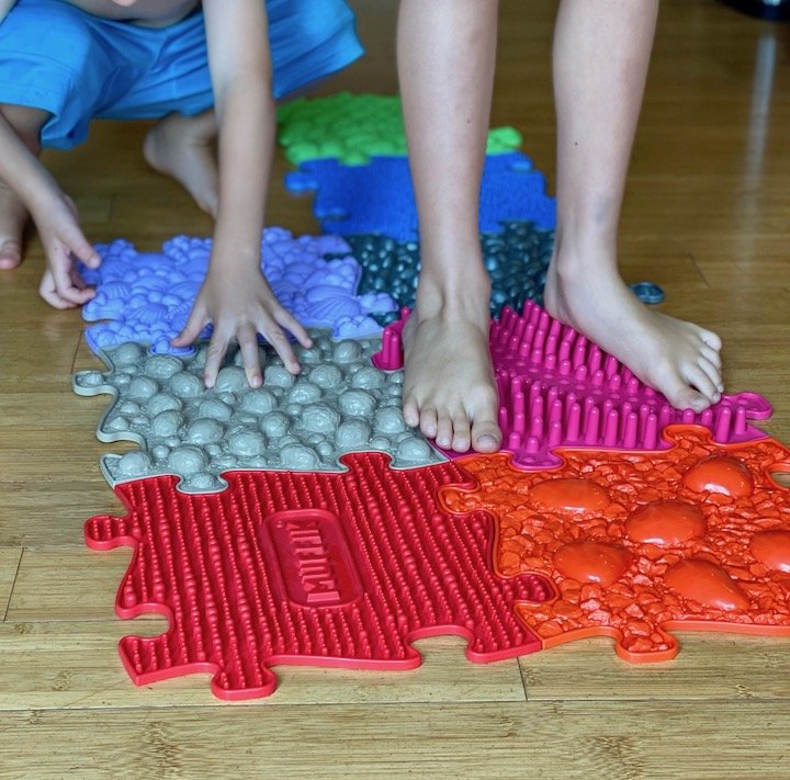 Two children standing or touching Muffik Orthopedic Floor Mats